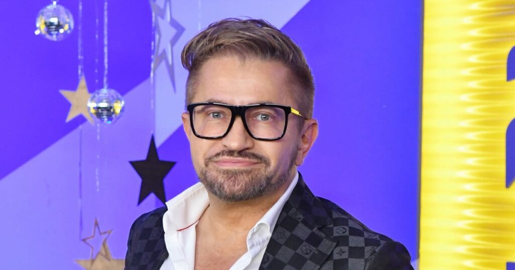 Jákob Zoli szemüvegben ingben színes háttér előtt