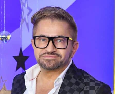 Jákob Zoltán szemüvegben ingben színes háttér előtt
