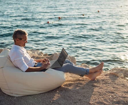 férfi laptop tengerpart babzsákon ül az ember