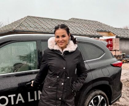 Nádai Anikó fekete kabátban áll egy luxusautó előtt